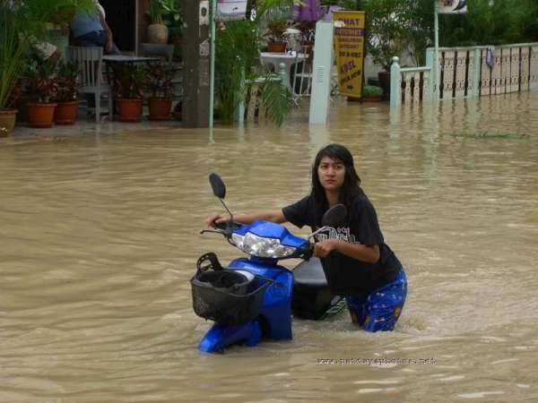 Pattaya lady pushing motorbike in flood waters